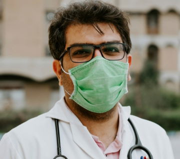 man in white scrub suit wearing green mask